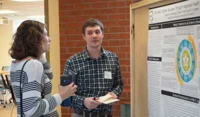 Allison Lombardi speaks with a graduate student who is presenting a poster at the Graduate Research Symposium.